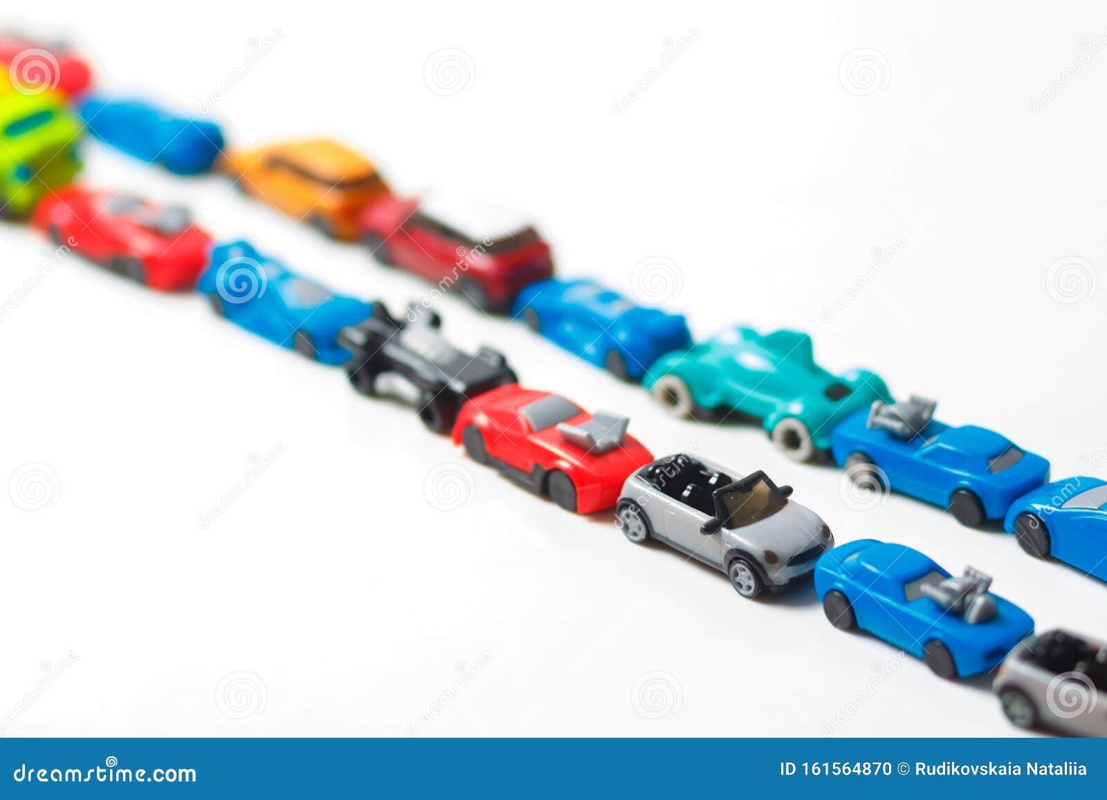 plastic multi-colored toy cars are lined up on a white background. stereotypical alignment of subjects is a sign of autism.