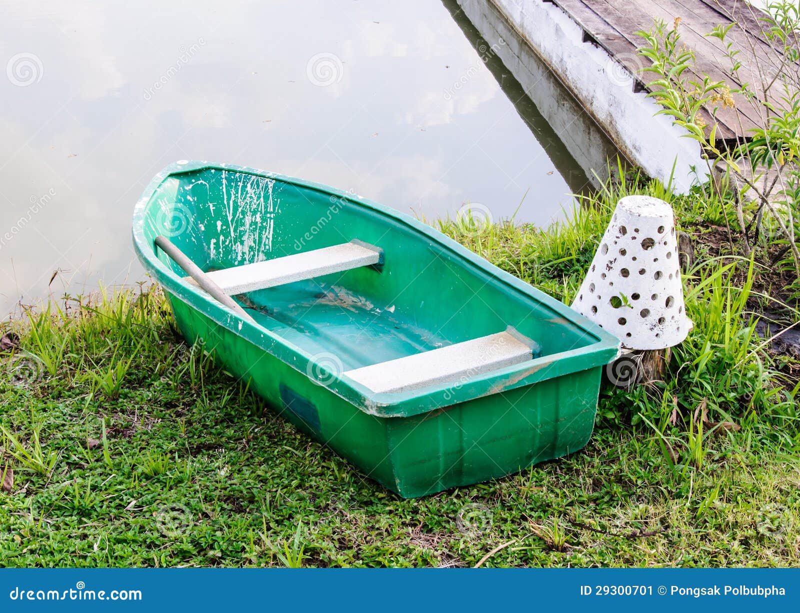 Plastic row boat near the wooden bridge of peaceful lake.