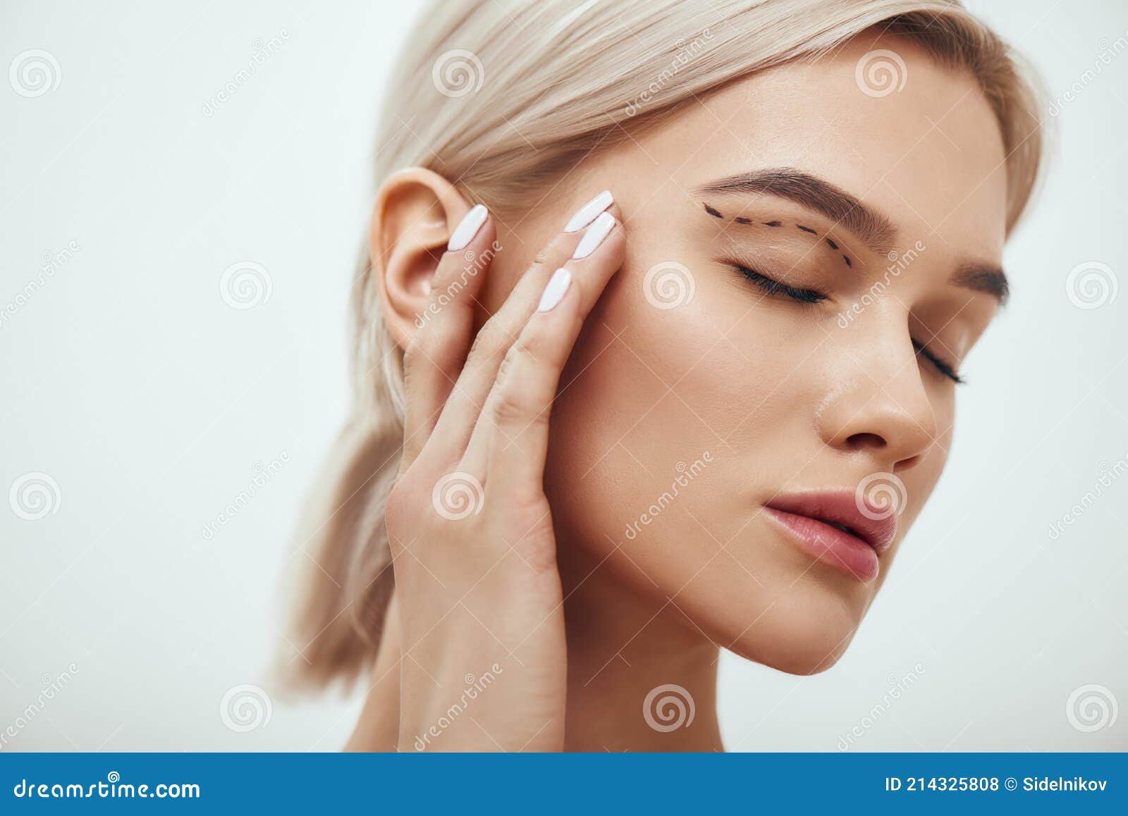 plastic surgery. beautiful young blonde woman keeping eyes closed and touching her face with sketch on it