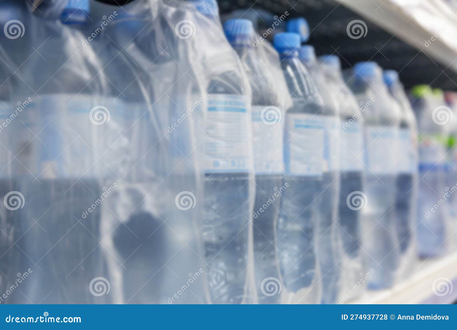Plastic Water Bottles in Packaging on a Shelf in a Store. Blurred Stock