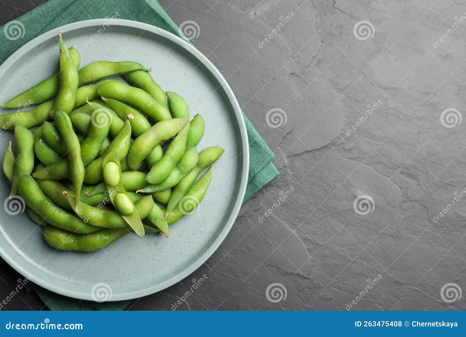 Plate of Green Edamame Beans in Pods on Black Table, Top View. Space