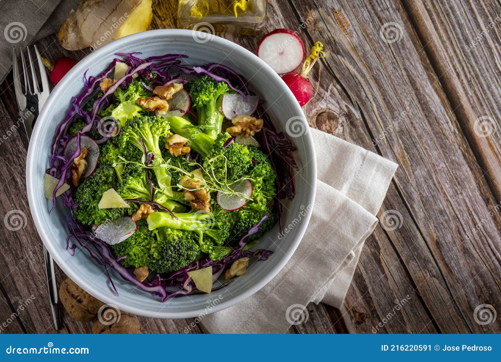 plate with a healthy vegetarian salad of steamed broccoli, fresh radishes, walnuts, red cabbage, ginger and extra virgin olive oil