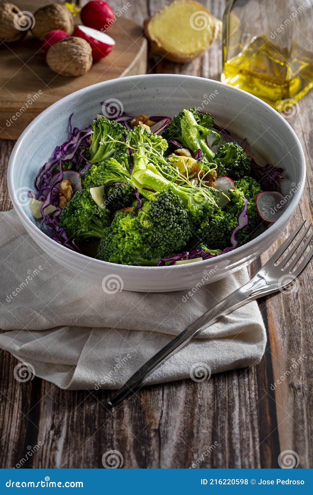 plate with a healthy vegetarian salad of steamed broccoli, fresh radishes, walnuts, red cabbage, ginger and extra virgin olive oil