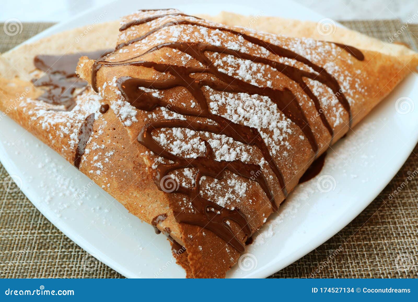 plate of mouthwatering french crepe with chocolate sauce and icing sugar