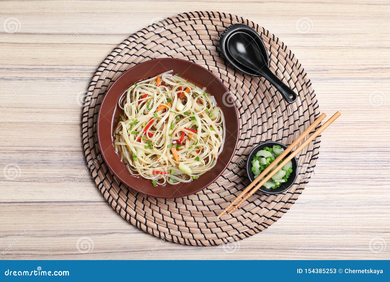 Plate Of Noodles, Broth And Vegetables Served With Chopsticks On Table