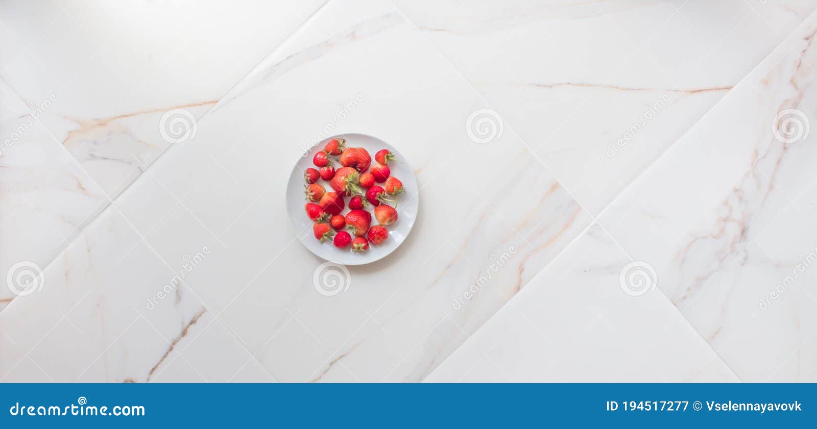 A Plate of Strawberries on White Marble Tile with Copy Space. Red Berries on a White Kitchen