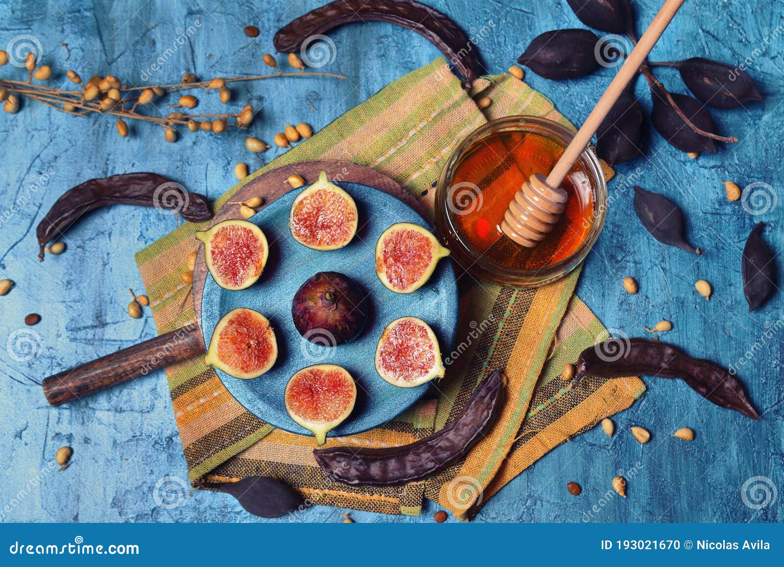 plate with three cut figs and one whole and container with honey