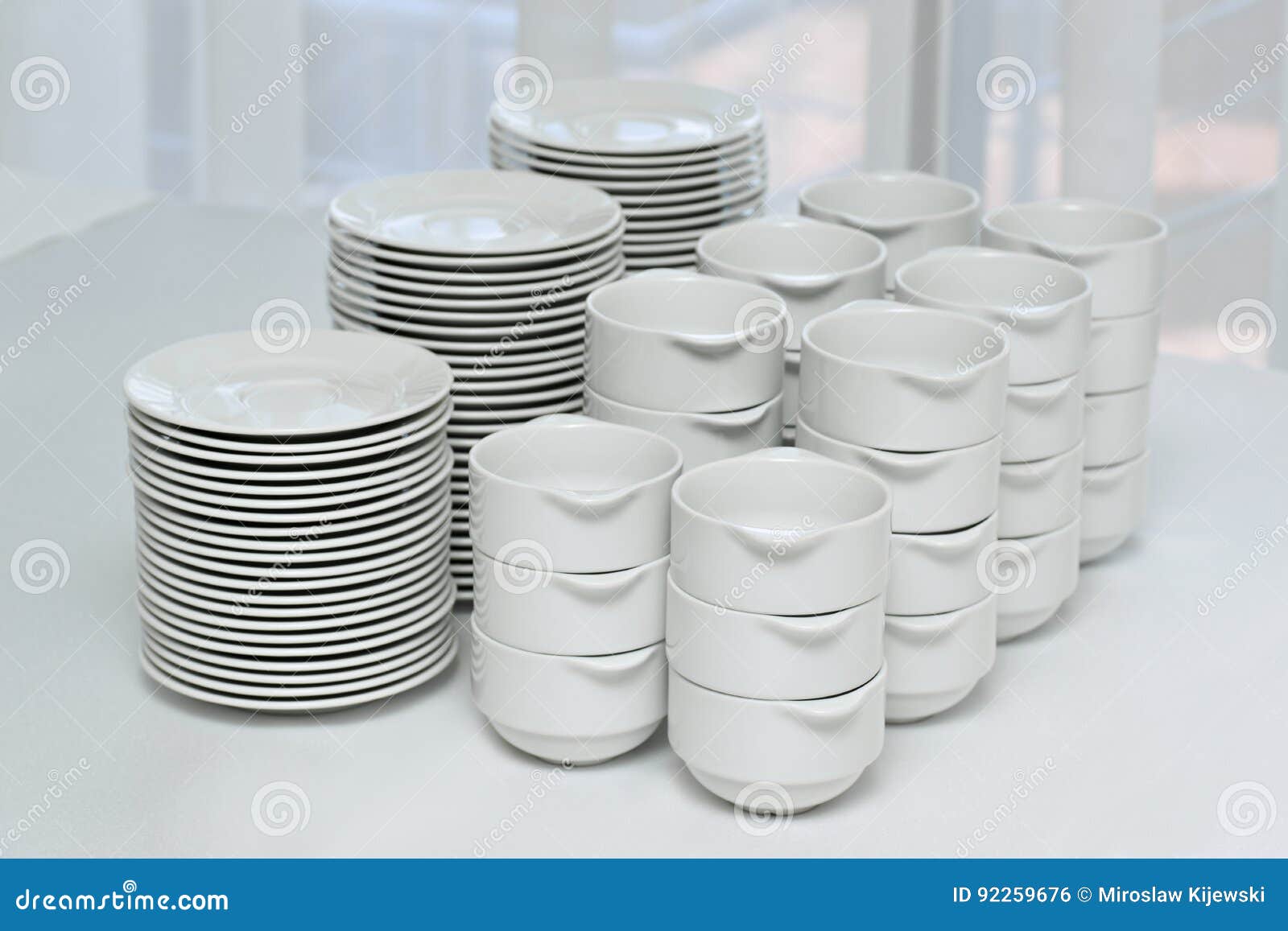 Plates and Bowls, White Ceramic on a White Tablecloth Stock Photo
