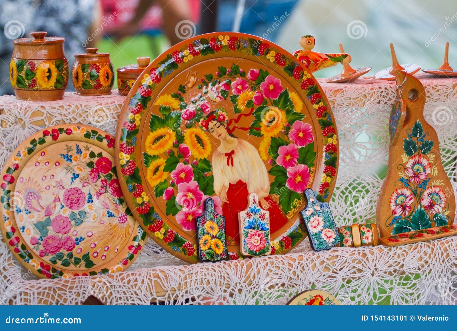 Plats en bois, fait main traditionnel et peint à la main avec une fille et un modèle floral lumineux à la foire de festival. Yakushyntsi, Ukraine - 22 06 2019 : plats en bois, fait main traditionnel et peint à la main avec une fille et un modèle floral lumineux à la foire vivante de festival d'Ethno de païen de milieu de l'été du feu