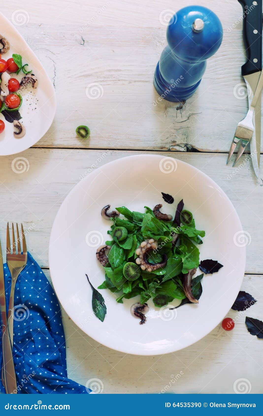 Eine Platte des grünen Salats mit Meeresfrüchten auf der Umhüllungs-Tabelle rustikal