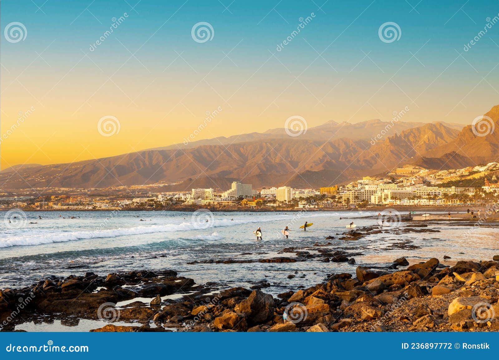 playa de las americas. surfers on the beach in tenerife at sunset