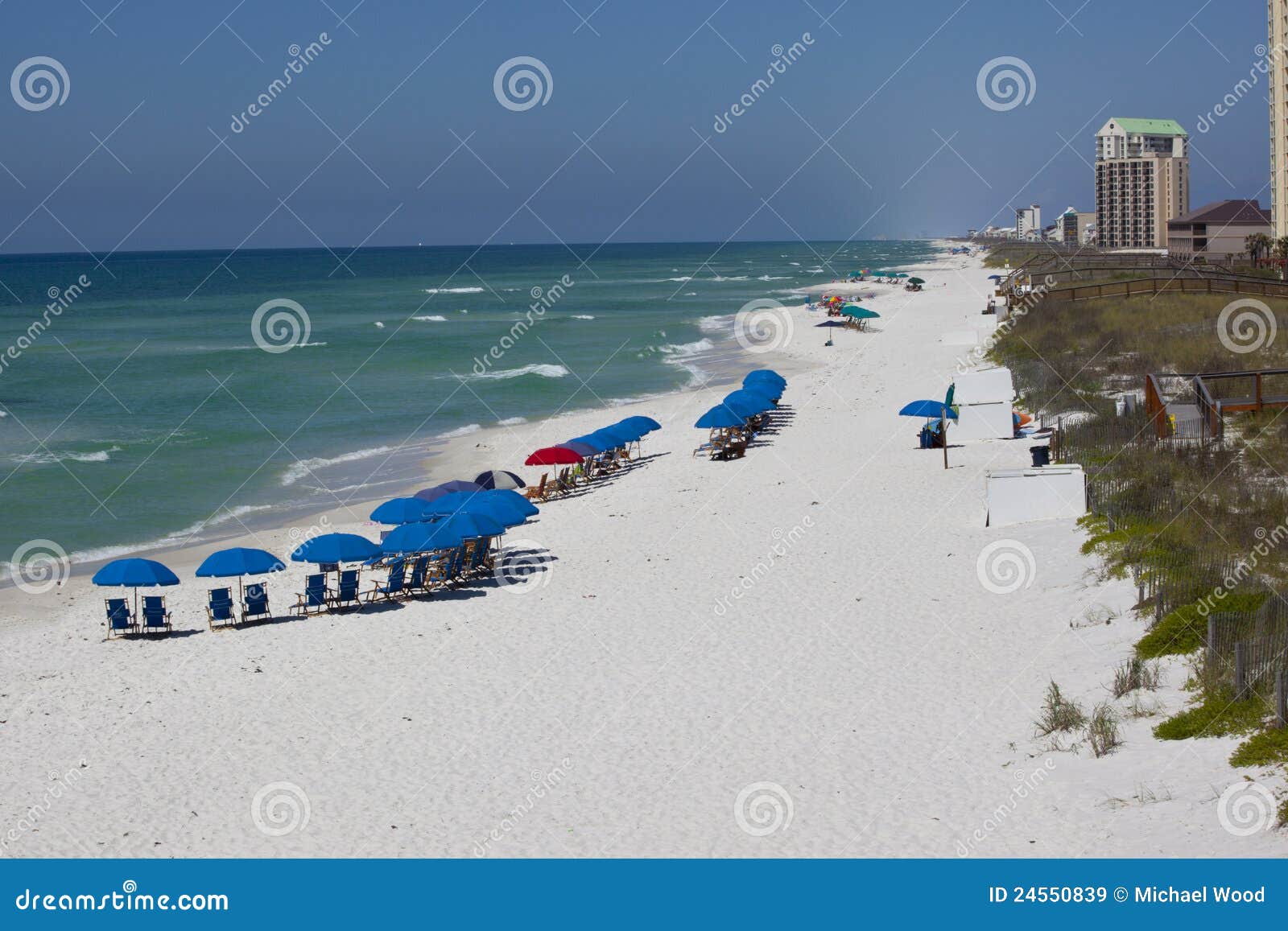 Playa de Navarra - la Florida. Los paraguas azules alinean la línea de flotación cerca del embarcadero en la playa de Navarra en un día asoleado en la Florida.