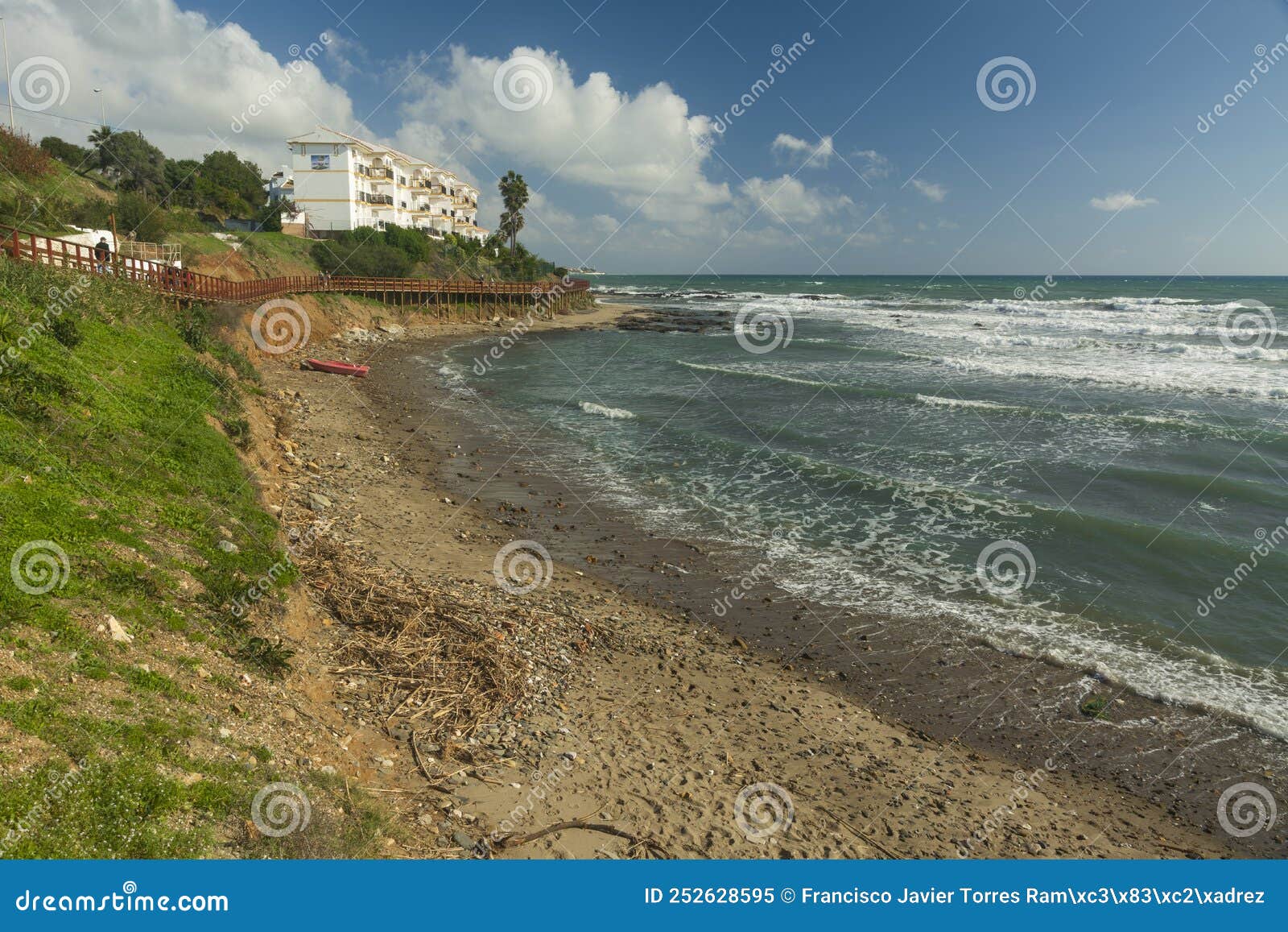 playa en el mediterraneo tras un temporal, con caÃ±as y maderas en la orilla