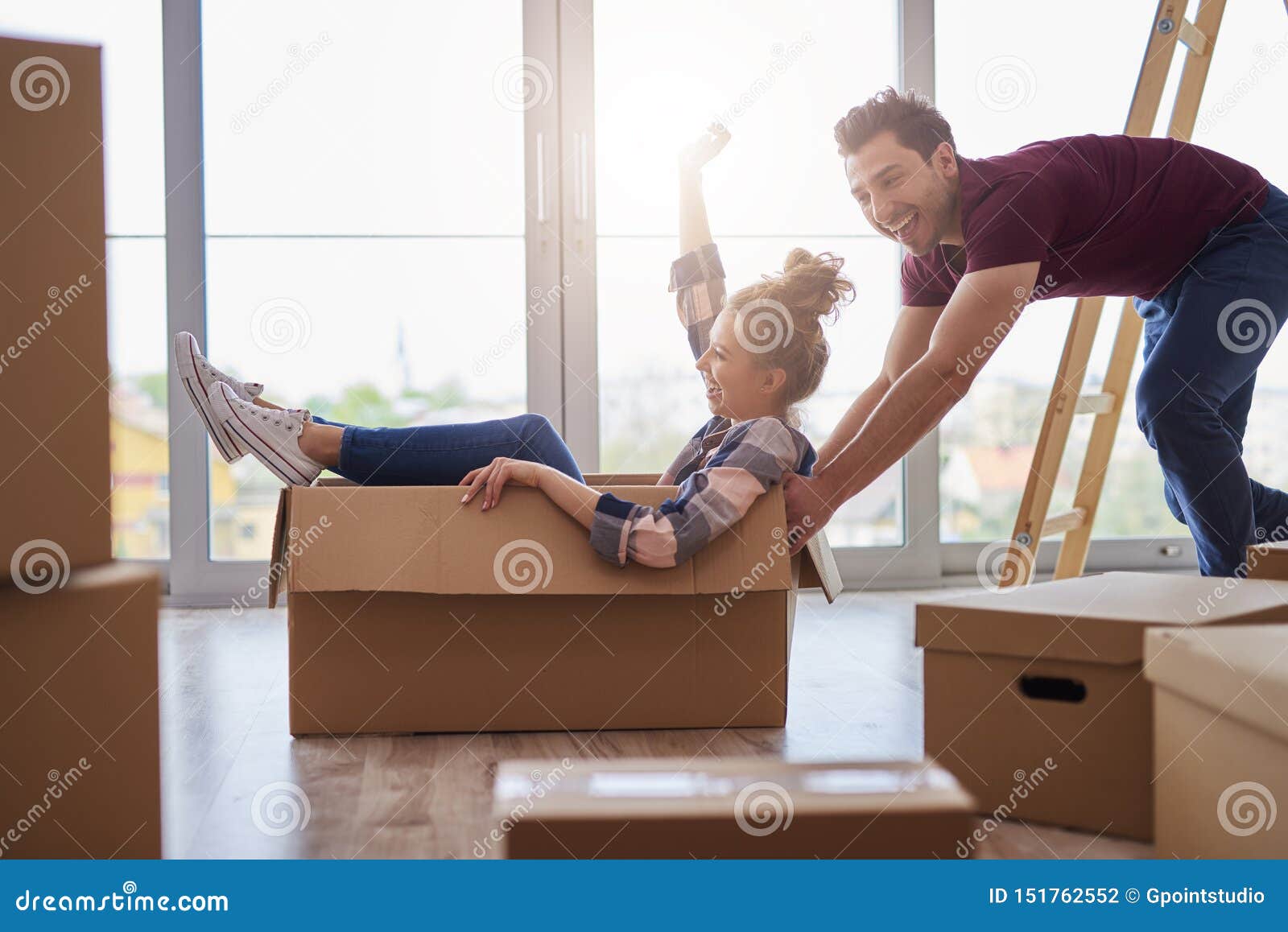 playful couple having fun with boxes during move house