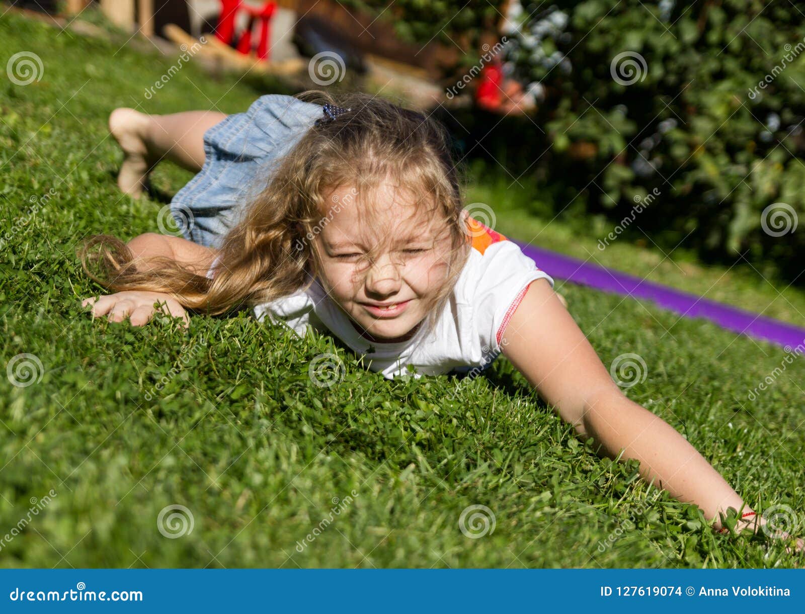 Playful Happy Little Girl Resting on a Grass in Summer Park Stock Photo