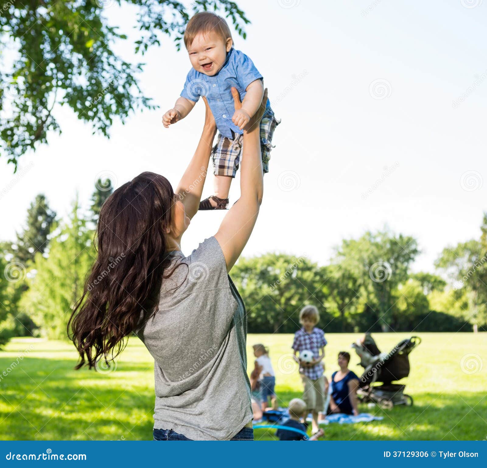 Playful Mother Lifting Baby Boy In Park Stock Photo ...