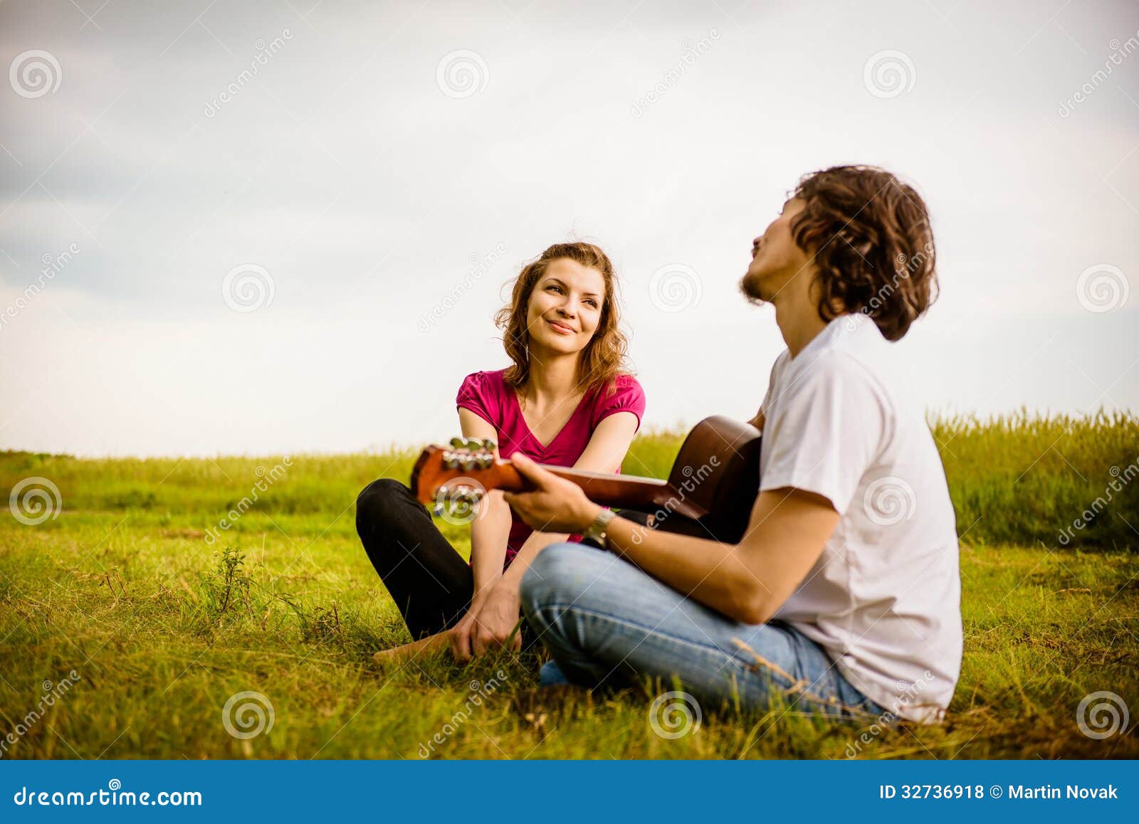 Playing guitar - romantic couple. Dating couple - young men playing to his girlfriend on guitar