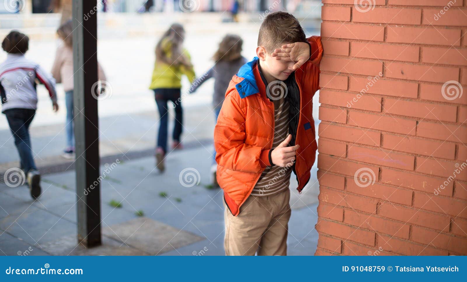 playing hide and seek. boy closed eyes his hands standing at brick wall