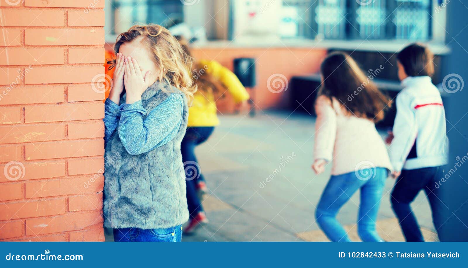 playing hide and seek. girl covering eyes her hands standing at