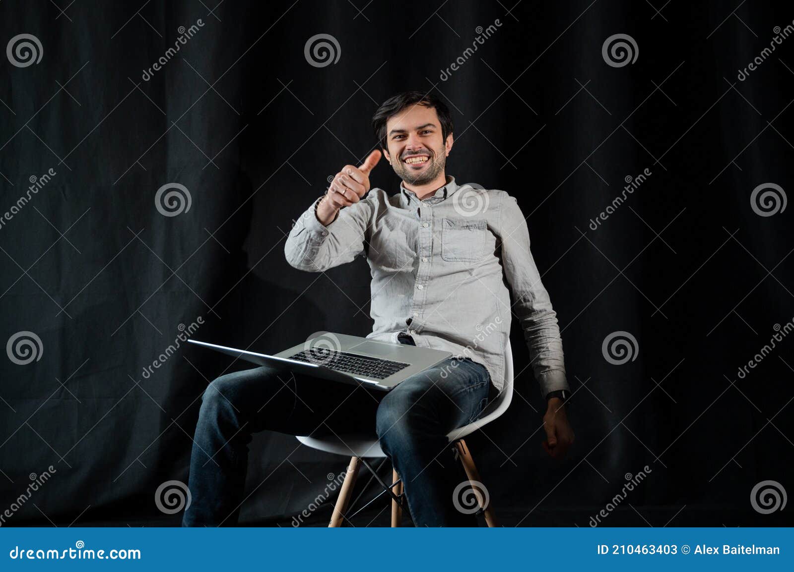 pleasant positive business man using laptop.happy smiling man in shirt works on laptop on a dark background