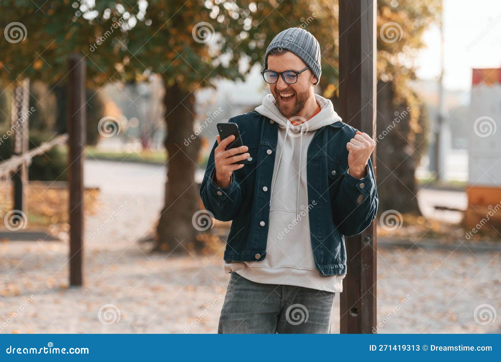 pleasantly surprised. with smartphone. beautiful man in warm clothes is outdoors in the park