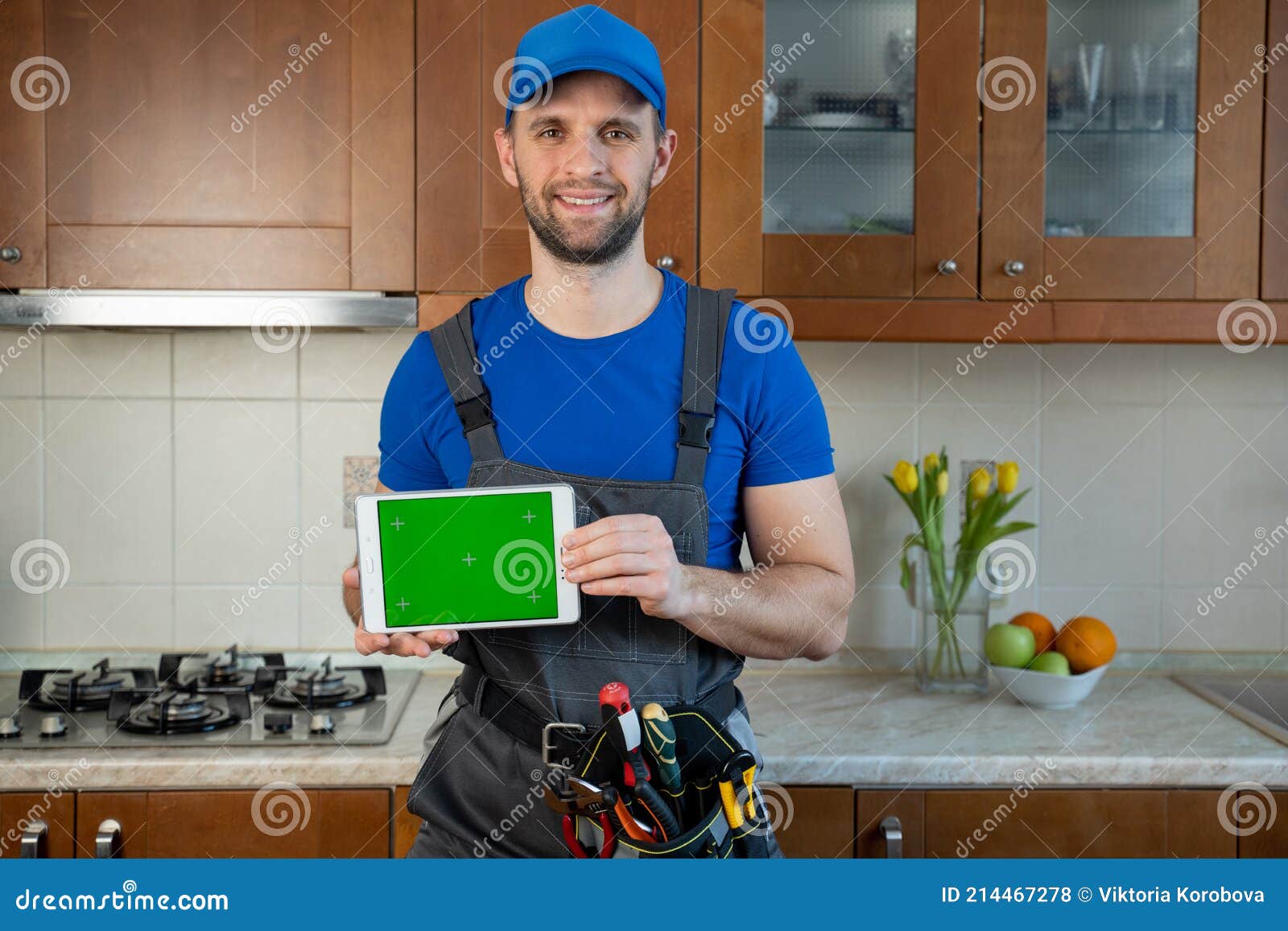 Plumber Holds a Digital Tablet with a Green Screen in the Kitchen Stock