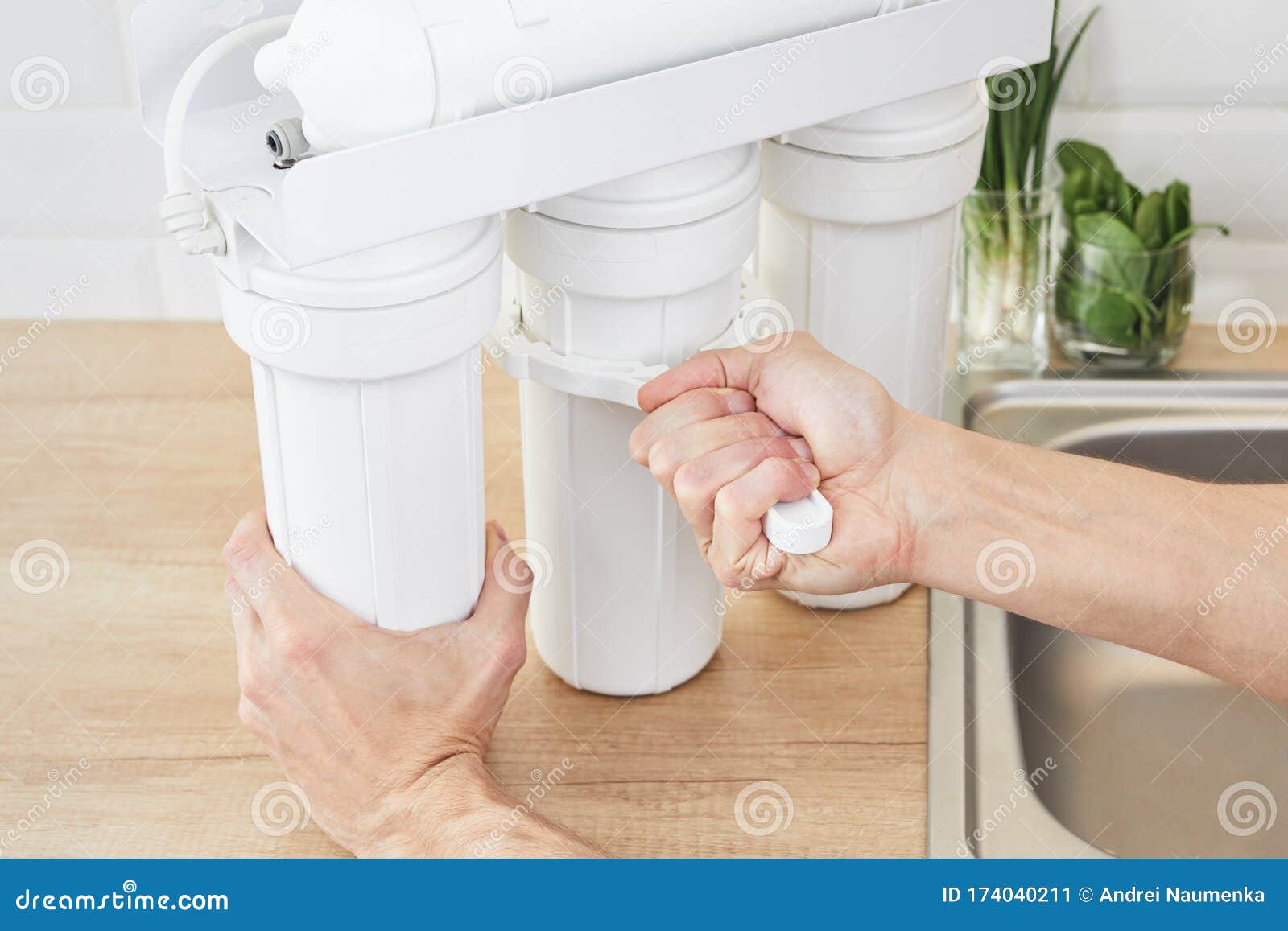 plumber or man hand holding installation key and replace a water filter cartridges at home kitchen. fix osmosis system