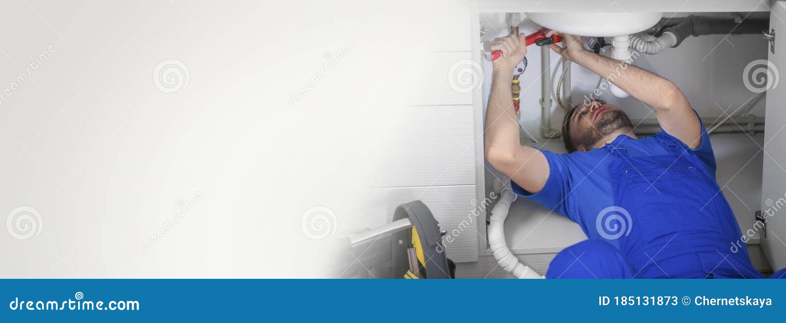 plumber in uniform fixing sink with pipe wrench space for text. banner 