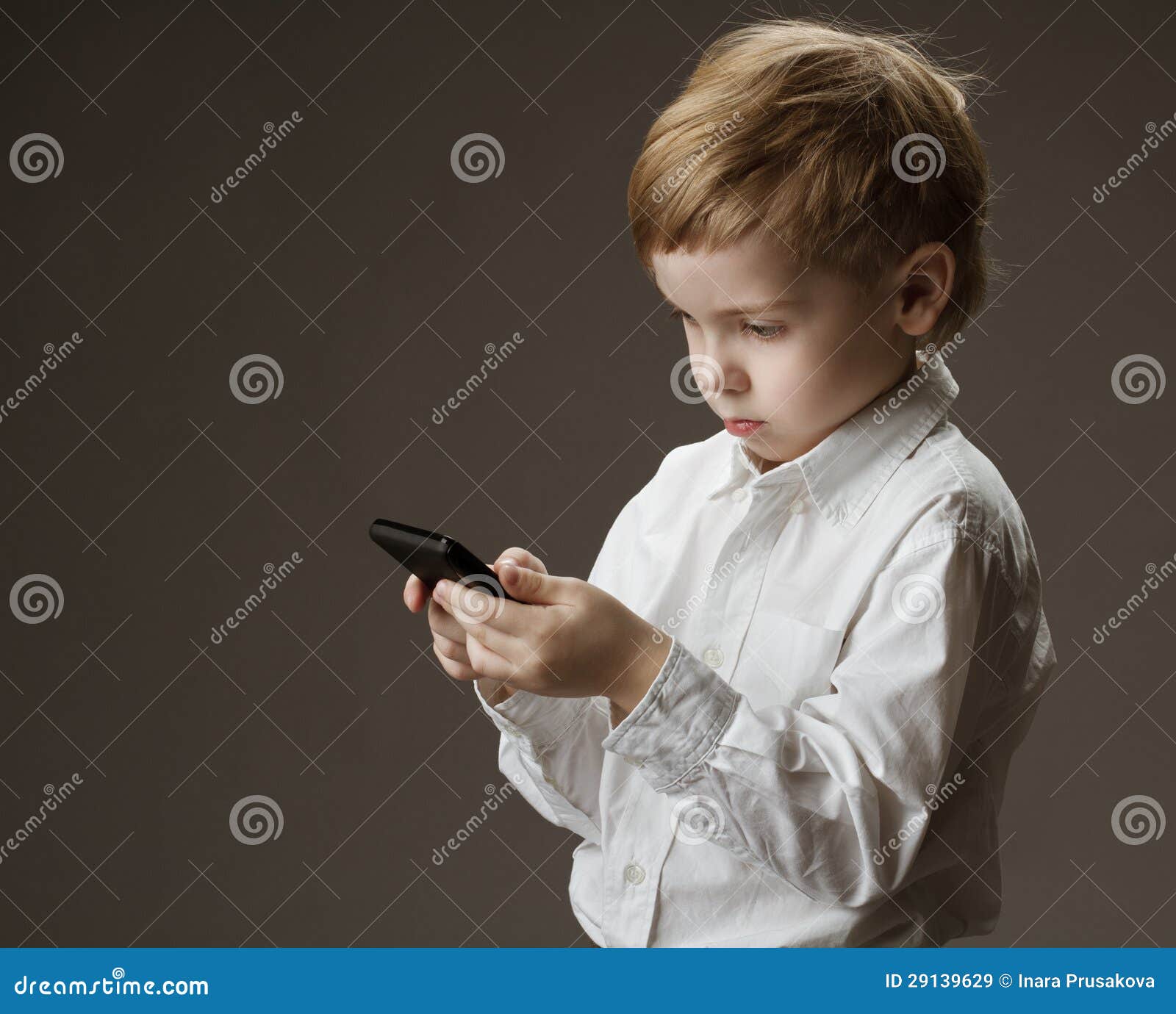 Pojken med mobil ringer. Pojken i hållande mobil för vitskjorta ringer