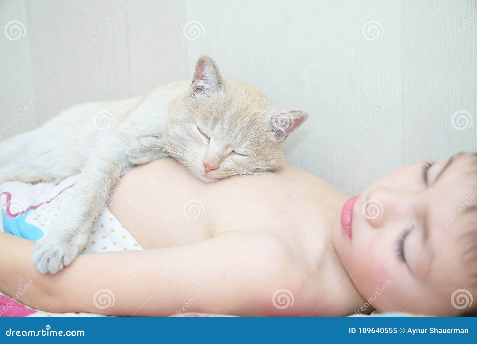 Pojkesömn med katten, favorithusdjuret som ligger på barnbröstkorg, växelverkan mellan barn och katter