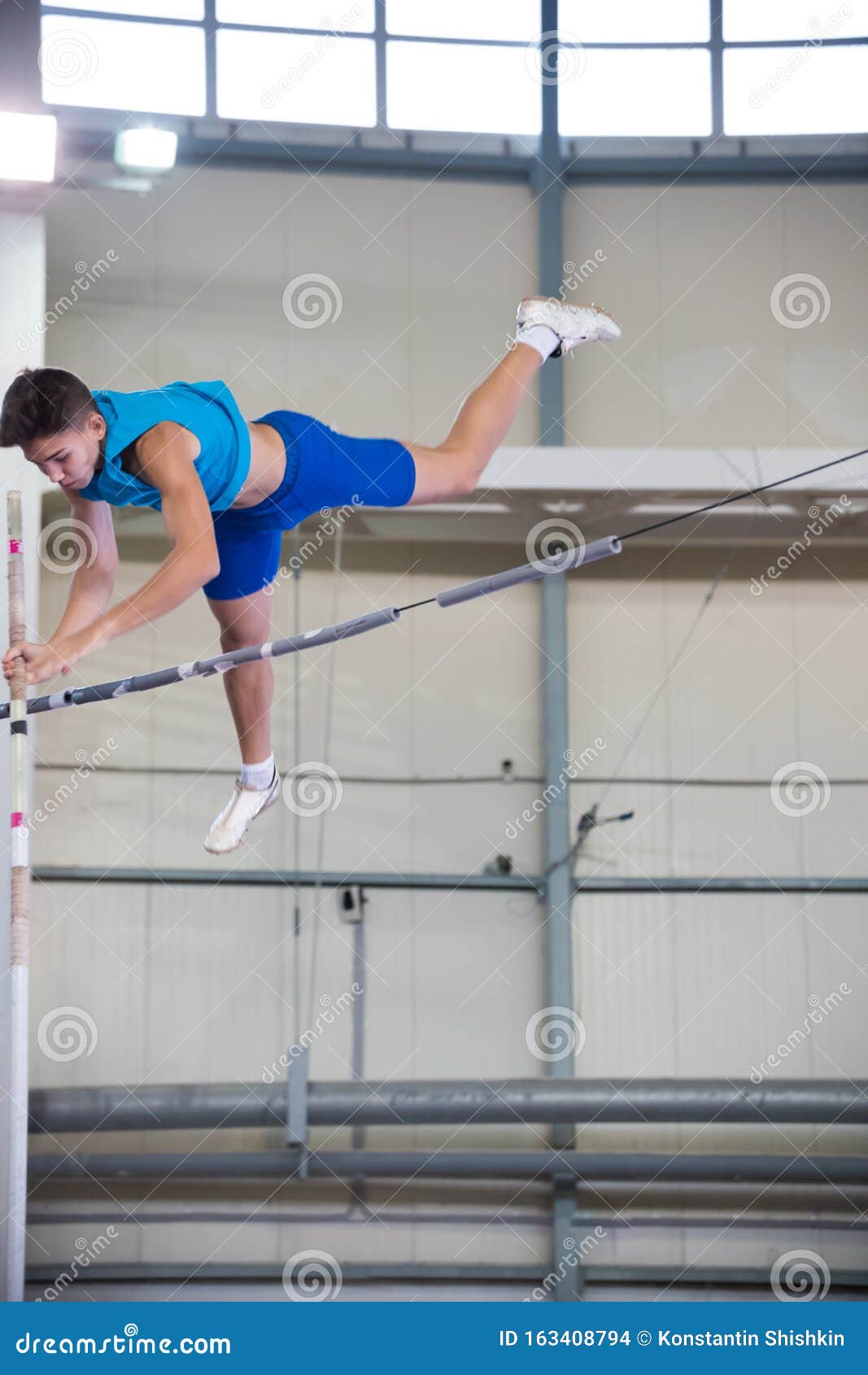 Pole Vaulting Indoors Young Man Flying Over the Partition Stock Photo
