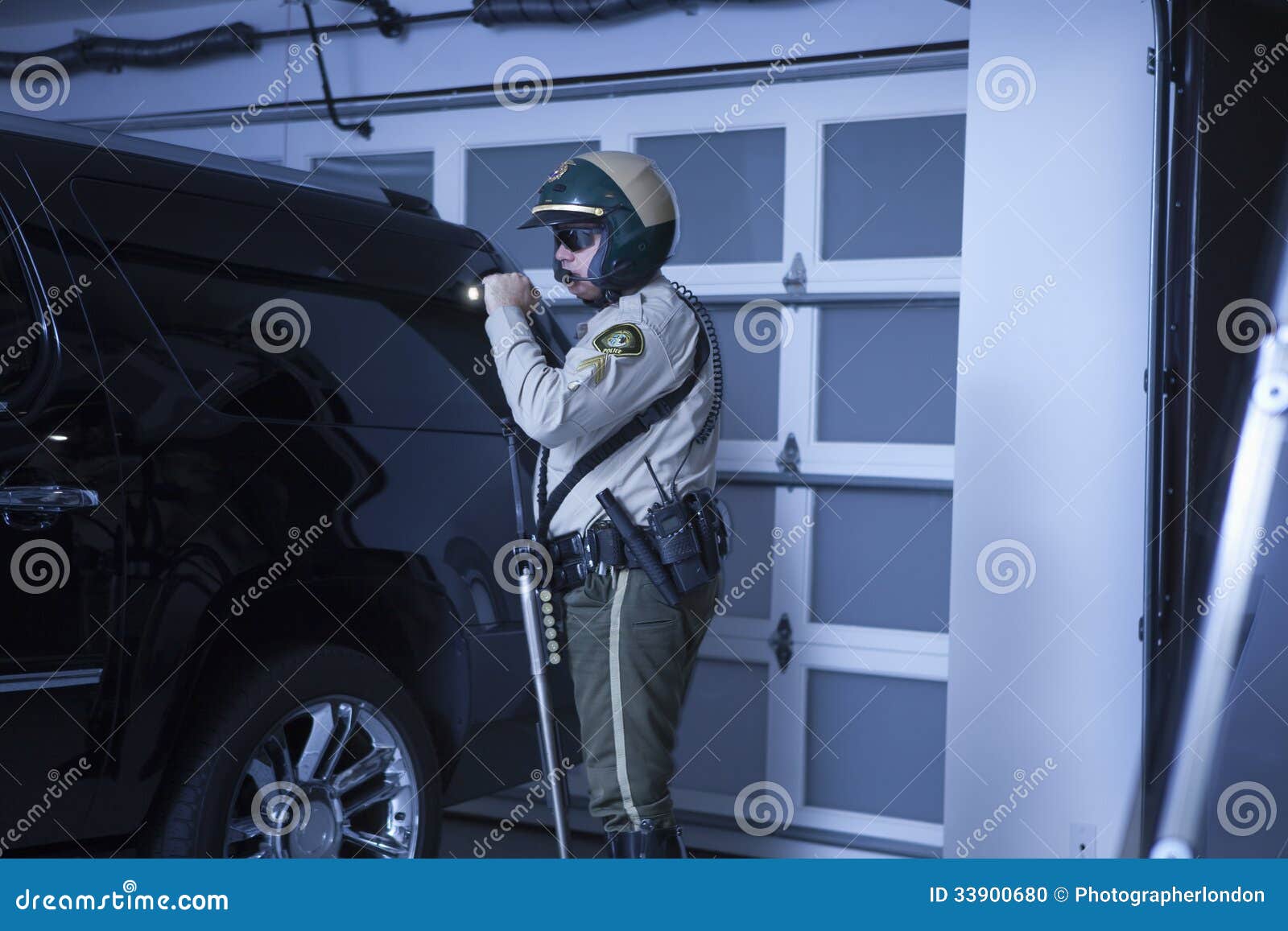 policeman with flashlight investigating car in garage