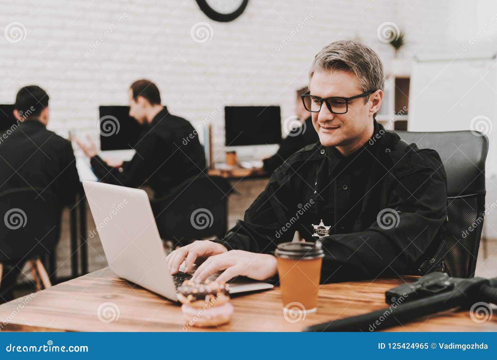 policeman works on laptop in a police station.