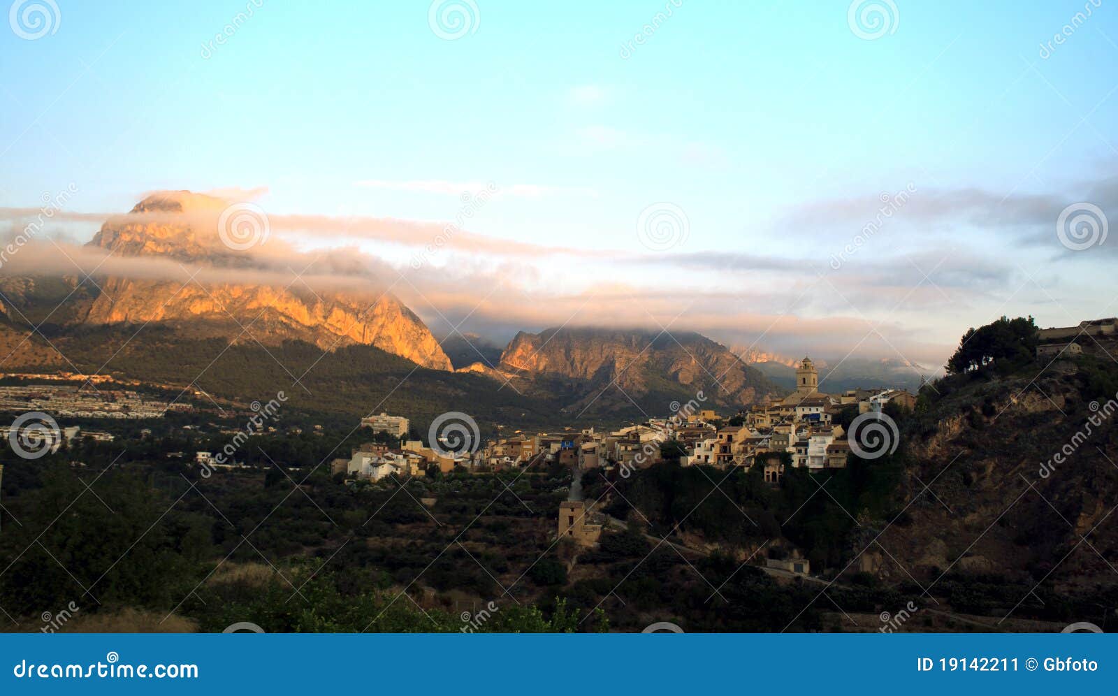 Das spanische Dorf von Polop am Sonnenaufgang mit Wolkenspuren über den Bergen genommen vom La Nucia