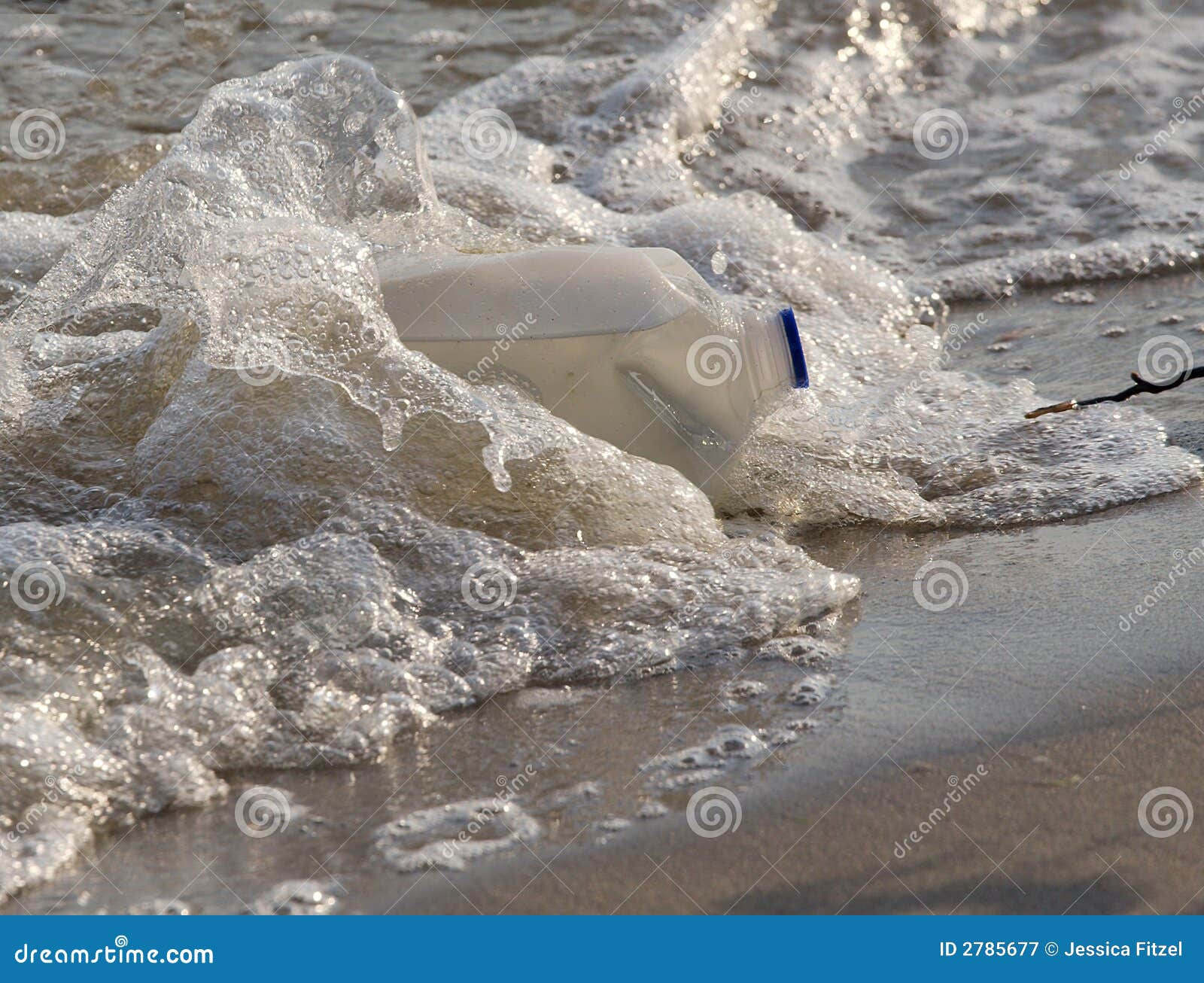 Poluição de água. O recipiente do leite do galão lavou acima na costa na praia na água contaminada.