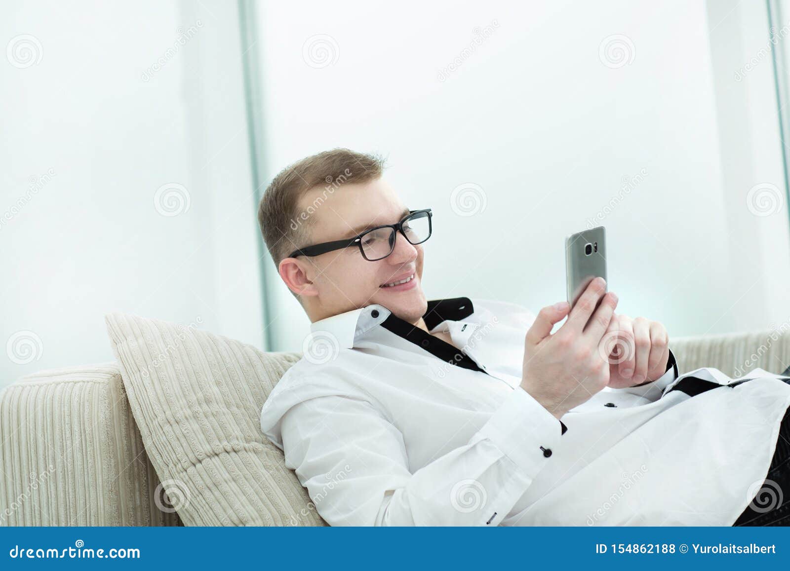 Pomyślny biznesowy mężczyzna pisać na maszynie podczas gdy czytający tekst na jego smartphone Ludzie i technologia