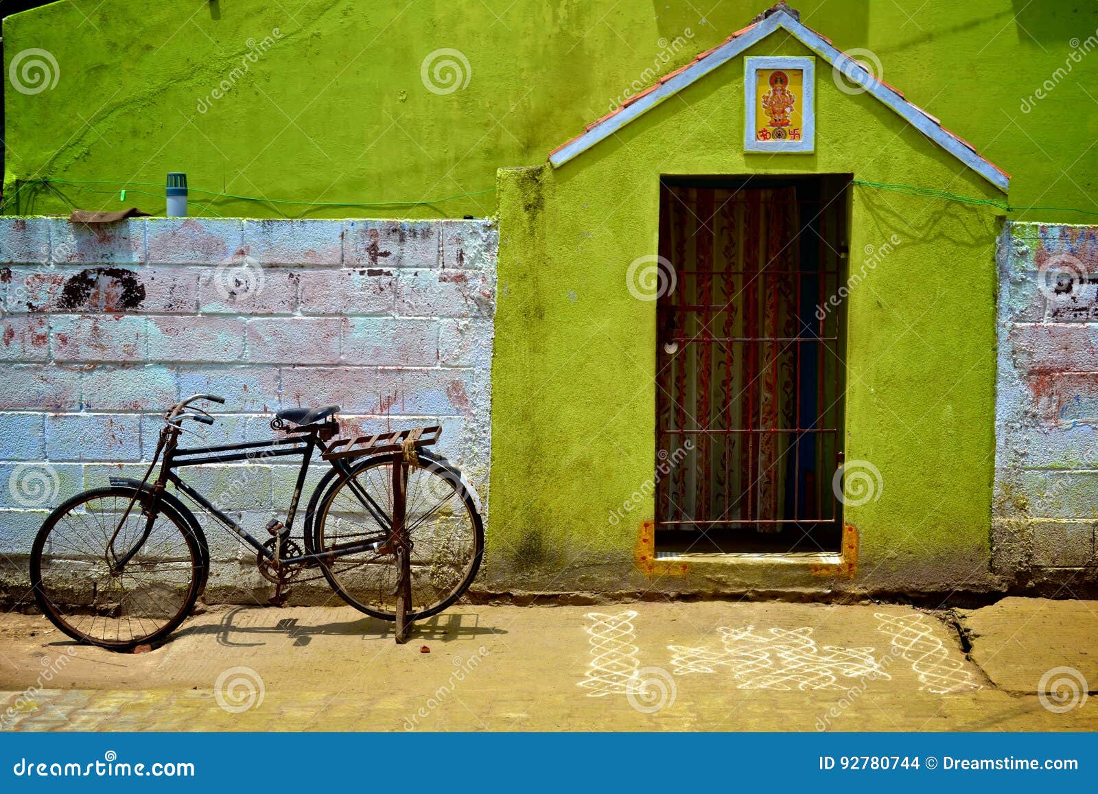 Pondicherry, bicicleta, porta e Kolam. Uma rua de Pondicherry com uma bicicleta indiana, uma porta, algum desenho no assoalho que chama Kolams