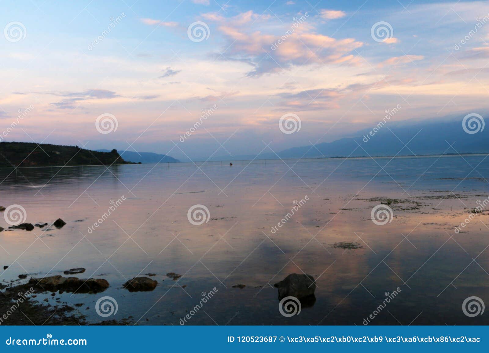Por do sol sobre o lago do lugu, Dali, yunnan, China. Dando um ciclo em torno da excursão do lago do lugu, o lago do lugu no crepúsculo no fundo do por do sol, parece particularmente quieto e bonito