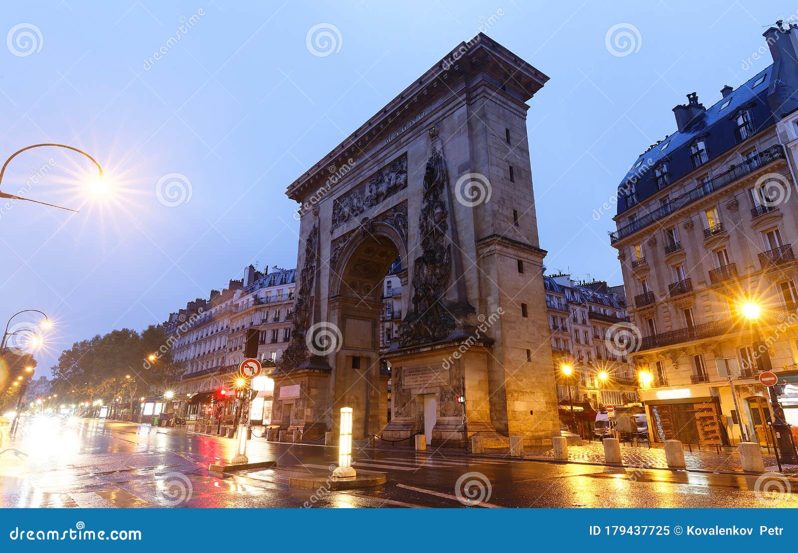 the porte saint-denis triumphal arch at rainy night , paris, france.