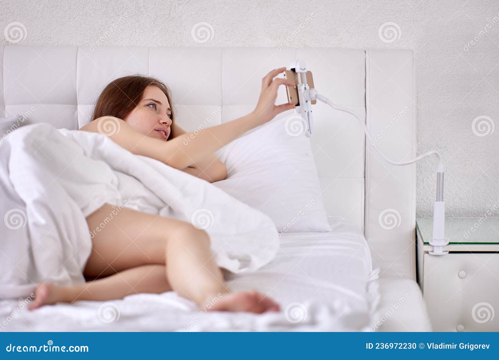 Porte-téléphone Fixe Près Du Lit La Femme Regarde Le Film Pendant Qu'elle  Est Allongée. Photo stock - Image du dame, support: 236972230