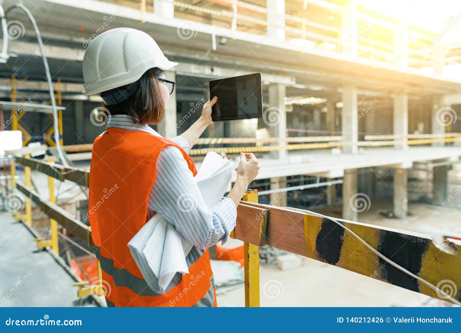 portrait of adult female builder, engineer, architect, inspector, manager at construction site. woman makes photo of building