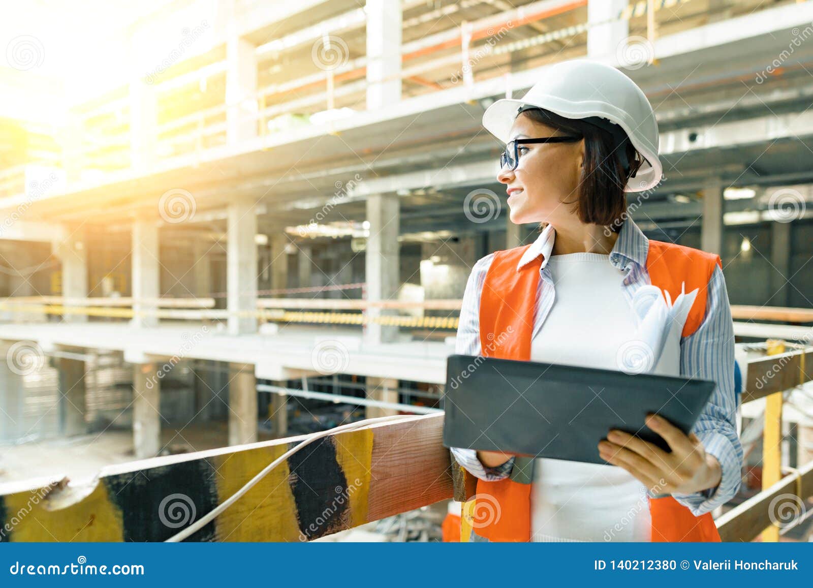 portrait of adult female builder, engineer, architect, inspector, manager at construction site. woman with plan, digital tablet