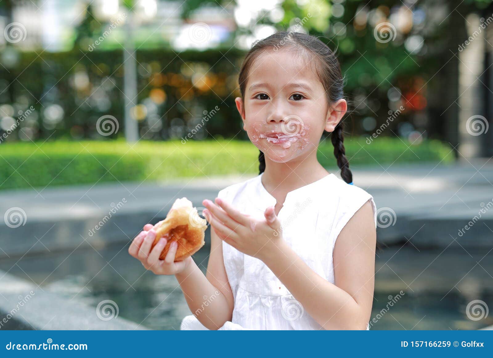 Portrait Of Asian Little Girl Eating Bread With Stuffed Stra