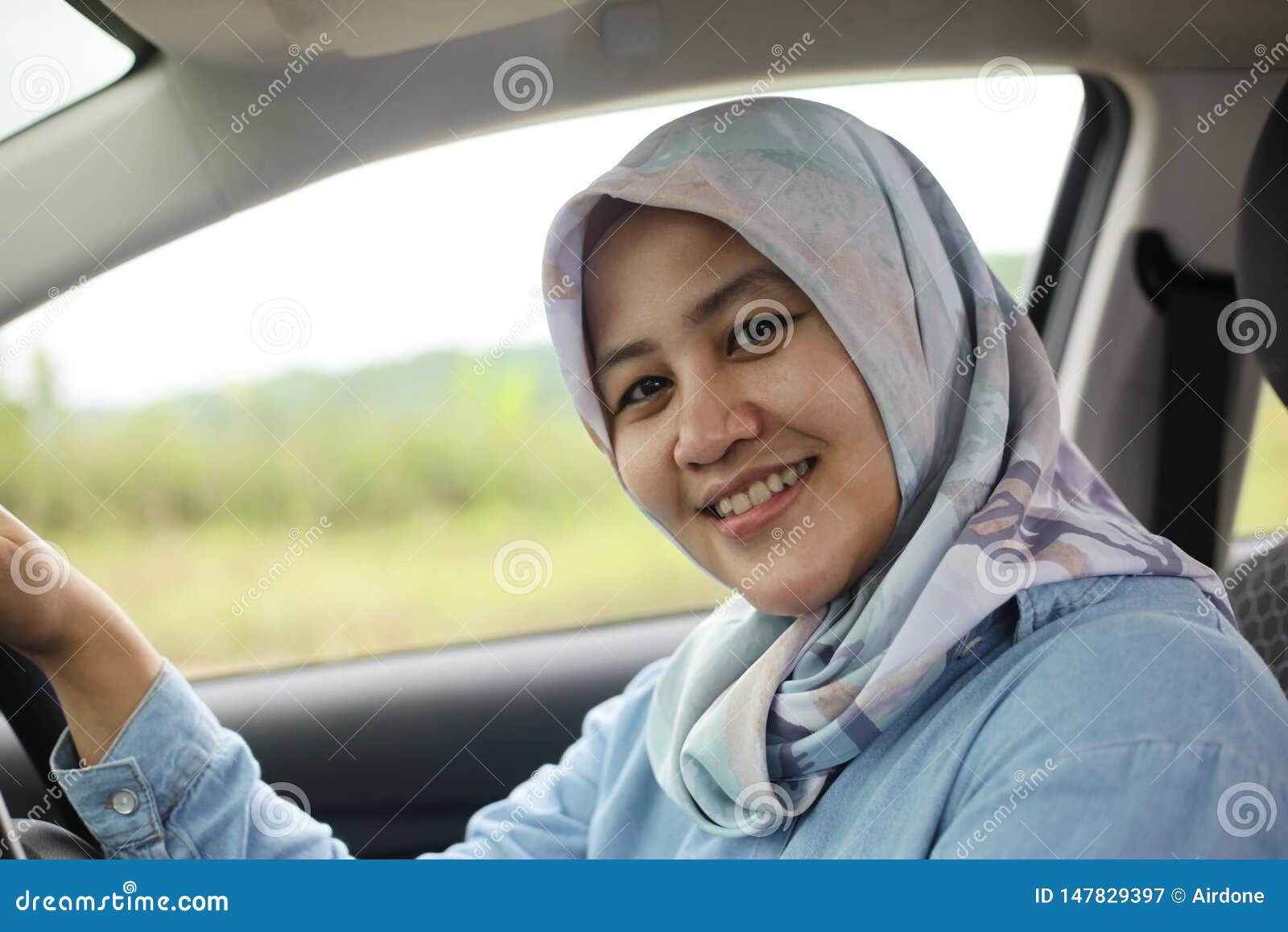 muslim lady driving her car and smiling