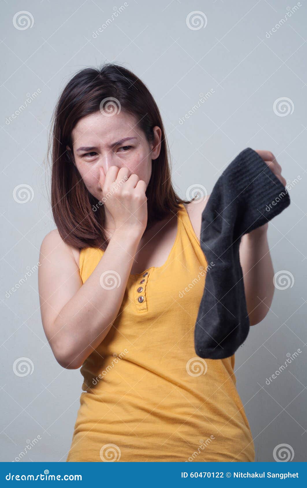 Portrait of Asian Woman in a Yellow Dress Smelling Socks Foul