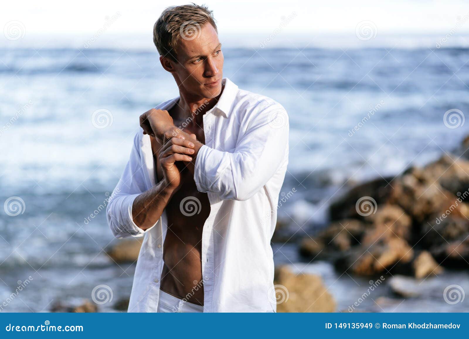 Portrait of Athletic Man in White Shirt Rests on Beach, Ocean at ...