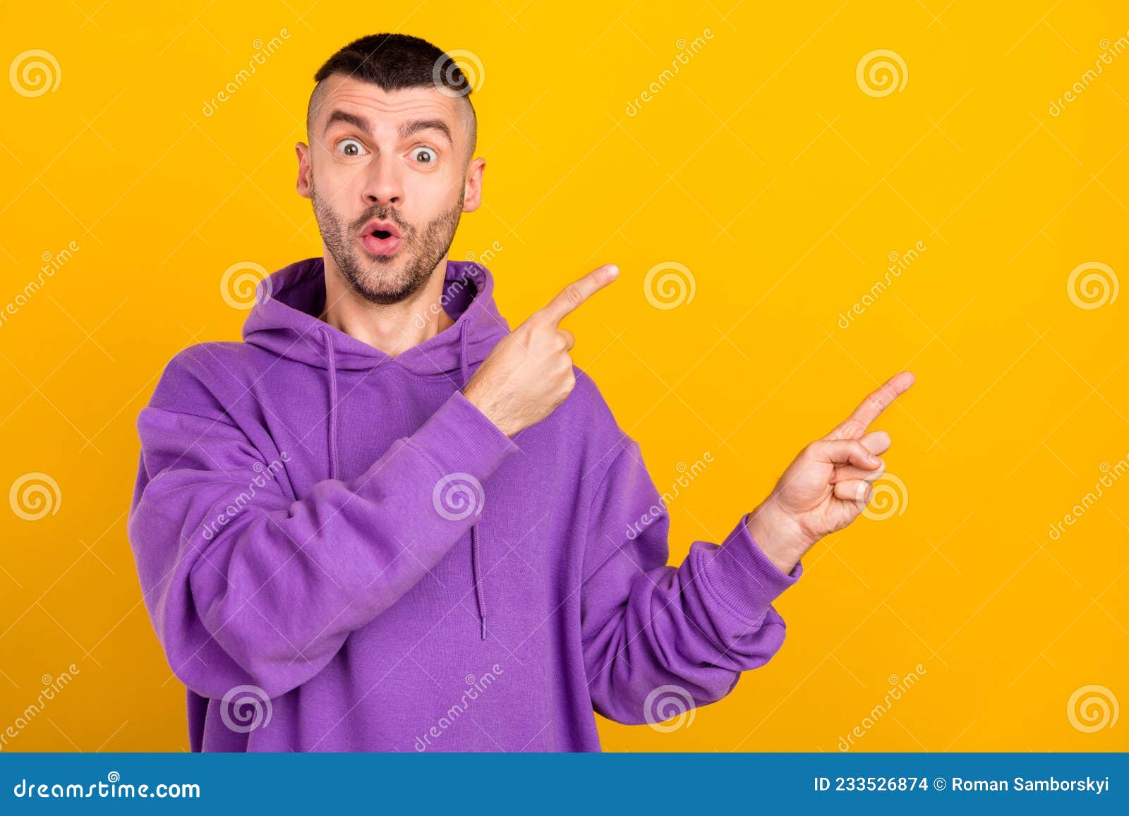 portrait of attractive cheerful amazed guy demonstrating ad copy blank space  over bright yellow color
