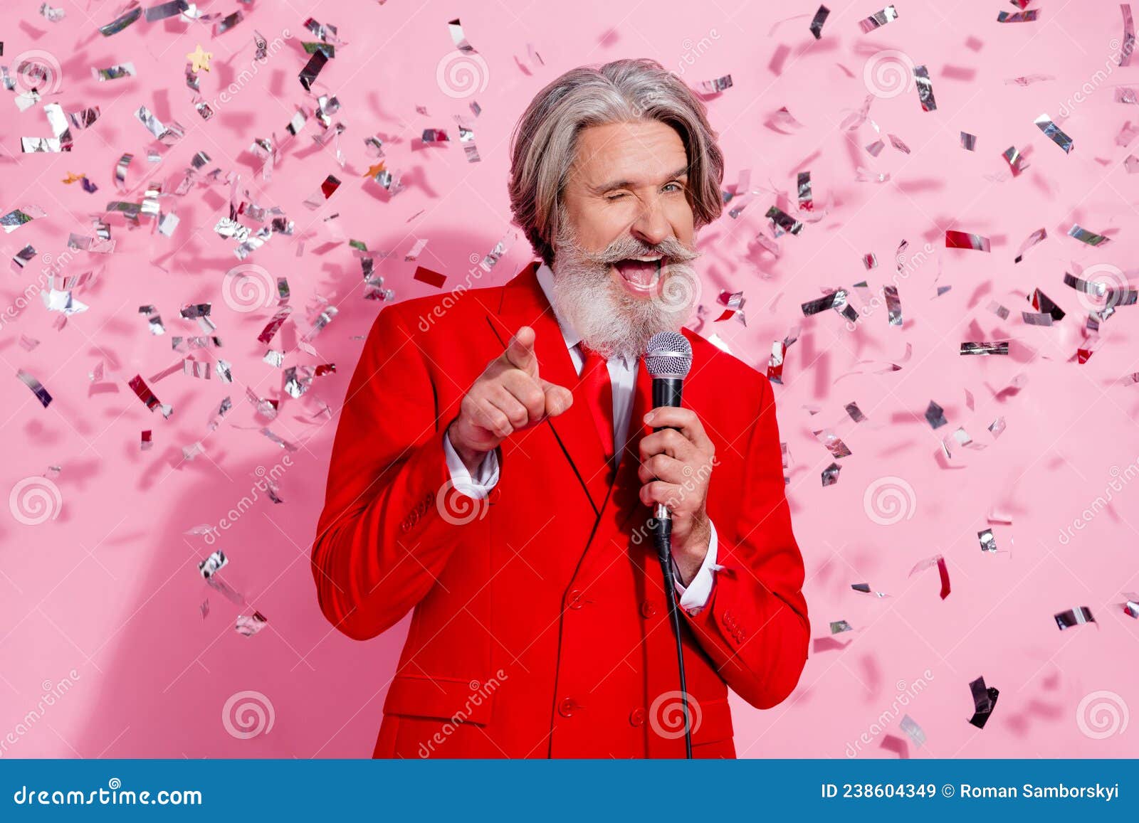 portrait of attractive cheerful cool trendy grey-haired man mc singing song winking anniversary  over pink