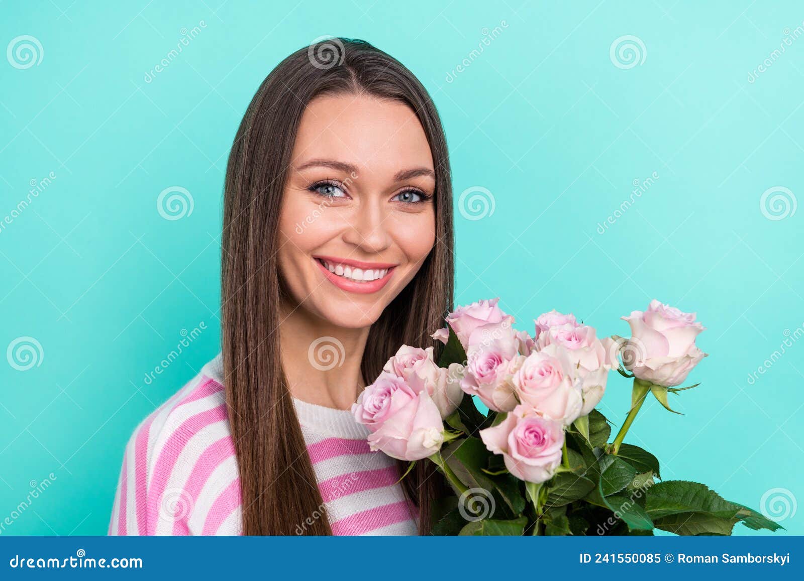 Portrait of attractive cheerful sweet cute girl smelling fresh pink roses isolated over bright teal turquoise color background.