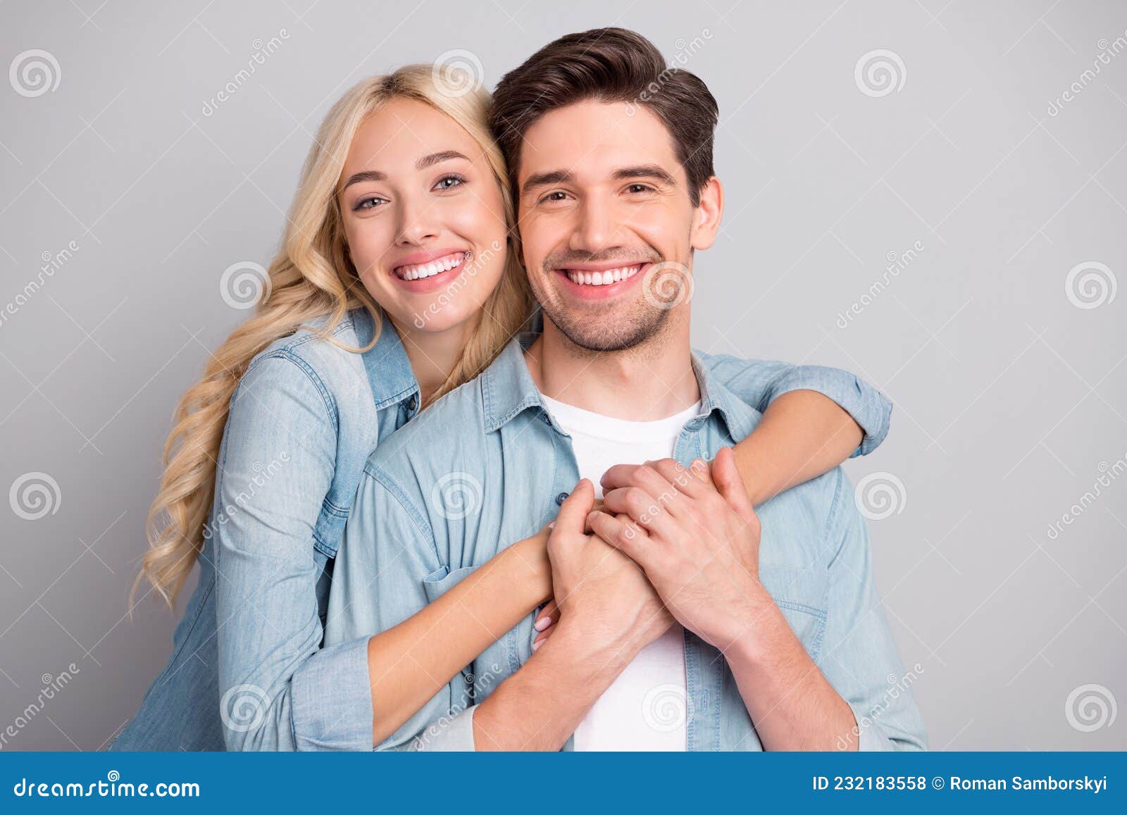 portrait of attractive cheerful tender couple life partners hugging bonding  over gray pastel color background